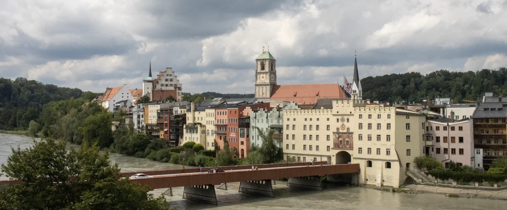 Blick auf die Häuserfront von Wasserburg am Inn. Im Vordergrund führt die Rote Brücke über den Inn in die mittelalterliche Stadt.